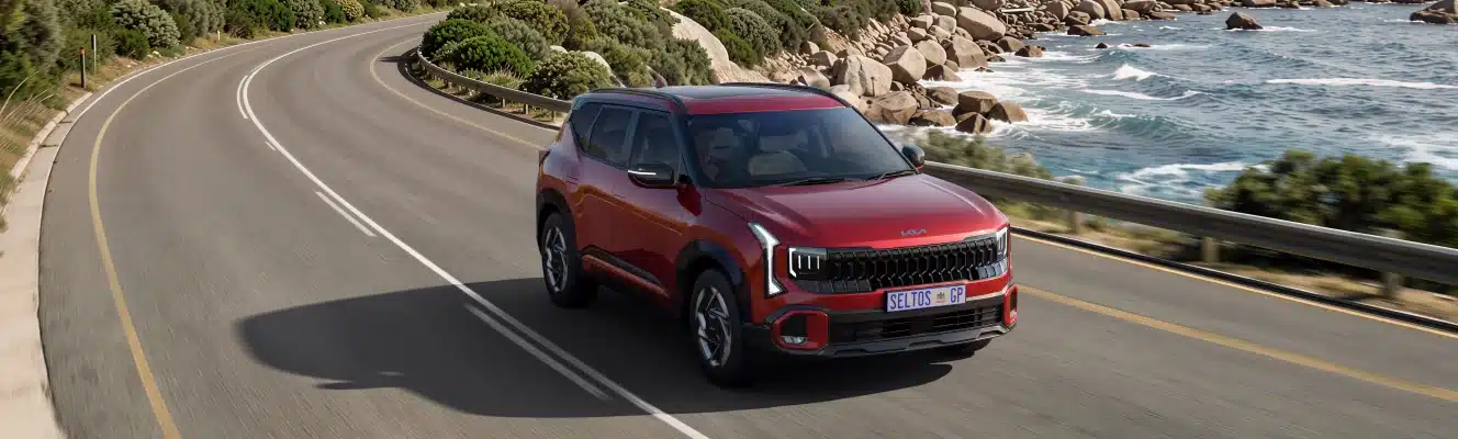 Red Kia Seltos on a coastal road