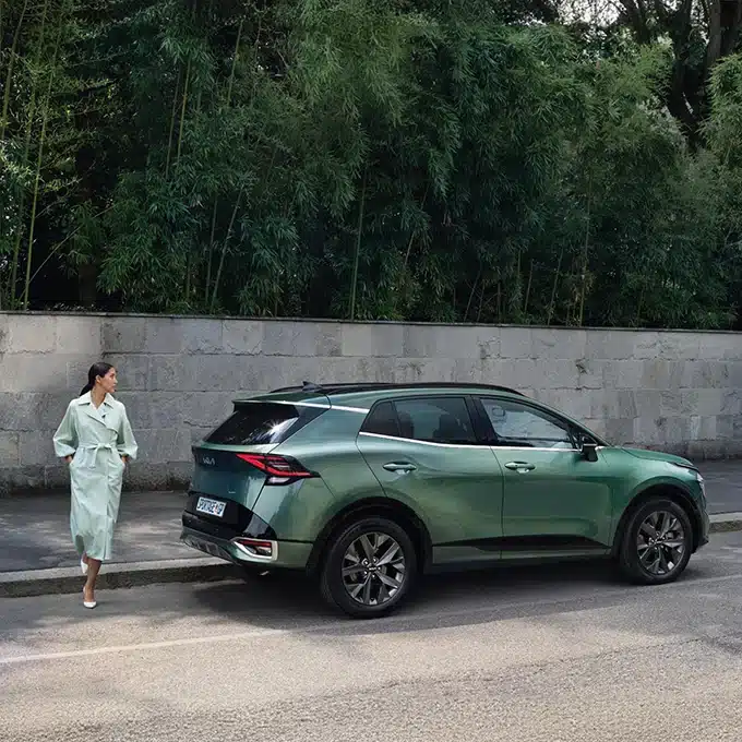 Green Kia Sportage parked beside a modern building
